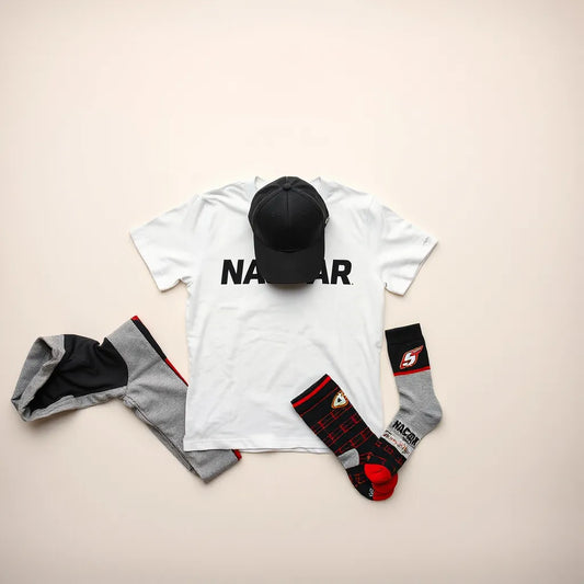 Flat lay of racing-themed T-shirt, cap, hoodie, jacket, and socks on a neutral background